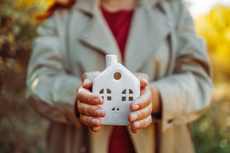Buy a house, take out a Bank loan or save up your money. Woman holding white house model in hand.Mortgage loan approval home loan and insurance concept.の写真素材