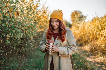 Photo of cheerful pretty relaxed 30s woman drinking coffee and smelling aroma in a park urban city street. High quality photoの写真素材