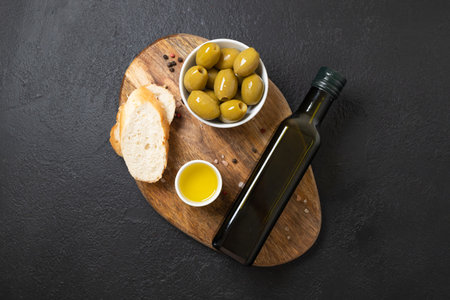 Organic Olive Oil, olives in bowls, sliced bread on cutting board over concrete background, top view, copy space. High quality photoの写真素材