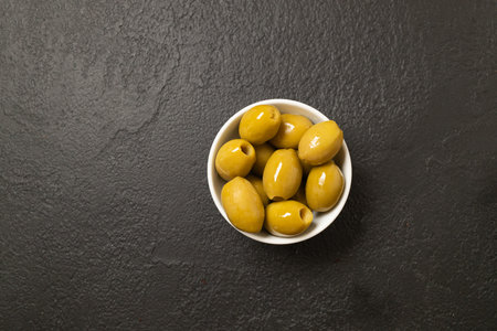 Whole green olives in a bowl on black background. Top view, close-up. High quality photoの写真素材