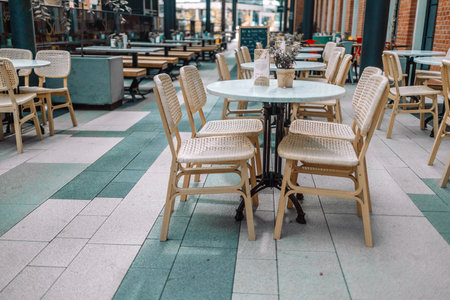 Wooden chairs with a green flowers in the middle of the table of an outdoor restarurant. High quality photoの写真素材