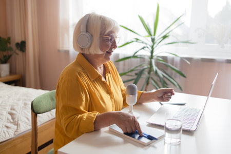 Female podcaster use smartphone and speaking with audience on microphone to recording video podcast. High quality photoの写真素材