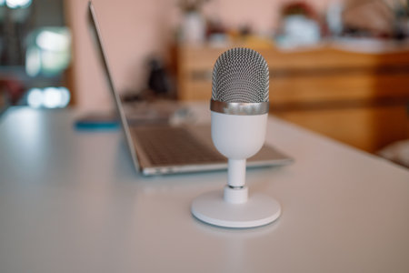 Closeup of a professional podcast microphone resting on a desk in a recording ready podcasting home studio. Selective focus of podcast equipment in empty room, ready to be used for online streaming. High quality photoの写真素材