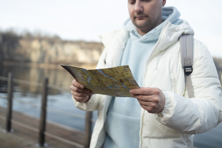 Hiker reading a geographic map choosing best trails. High quality photo