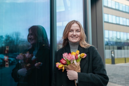 Beautiful happy Caucasian woman smelling bunch of tulips with closed eyes.の写真素材