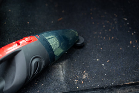 Details of car vacuum cleaning. Professional cropped male worker using wet vacuum cleaner for dirty car interior. Auto car service cleaning the drivers seat, cleaning and vacuuming concept. High quality photoの写真素材