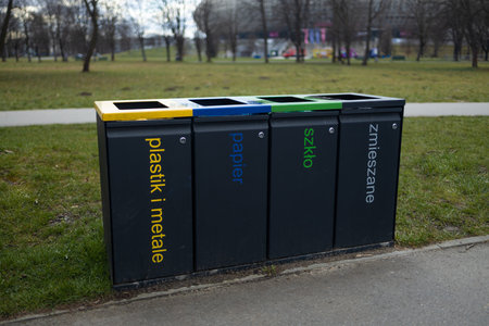 Four separate trash bins for recycling in the park, each labeled for plastic, paper, metal, and general waste. The color coded bins support environmental efforts for waste sorting and recyclingの写真素材