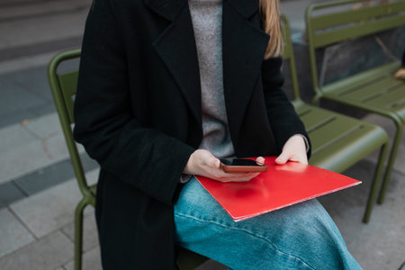 Photo of successful confident business lady holding folder with documents while sitting on street...