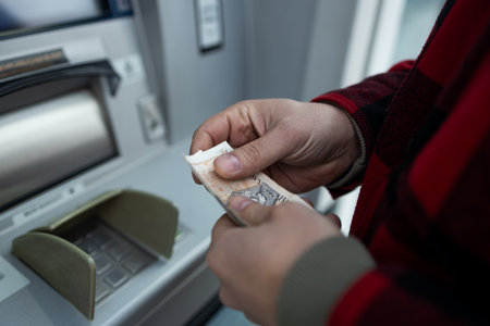 A person withdrawing cash in Polish zloty from an ATM. The image shows the convenience of accessing local currency through automated teller machines in Polandの写真素材