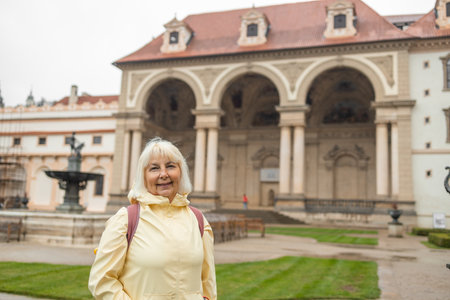 Woman tourist walks around along a decorative alley decorated with many statues in a decorative park at Wallenstein Palace building in Prague in Czech Republicの写真素材