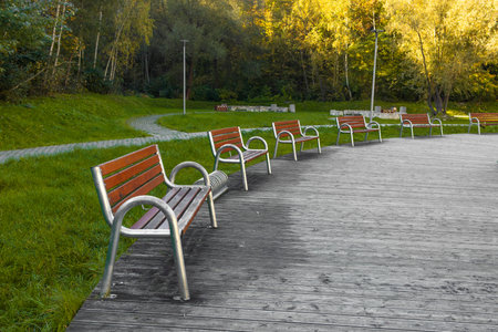 A modern wooden benches with trash bin standing in the park. Comfortable bench in recreation area. City improvement, urban planning, public spaces. High quality photoの写真素材
