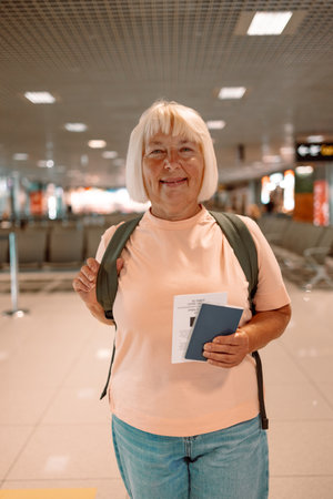 Happy blonde hair Elderly female tourist with a backpack with a passport while waiting for the passport check of the tourist at the airport. High quality photoの写真素材