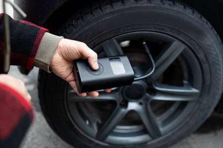 man driver hand inflating tires of vehicle, removing tire valve nitrogen cap for checking air pressure and filling air on car wheel at gas station. self service, maintenance and safety. High quality photoの写真素材