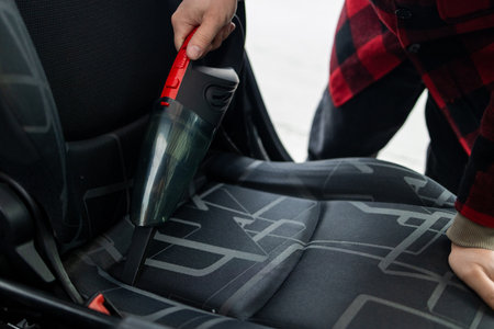 Details of car vacuum cleaning. Professional cropped male worker using wet vacuum cleaner for dirty car interior. Auto car service cleaning the drivers seat, cleaning and vacuuming concept. High quality photoの写真素材