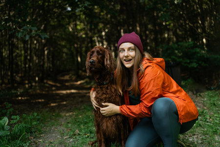 Woman and dog enjoying a hiking adventure in the forest. She is holding the dog gently while sitting...
