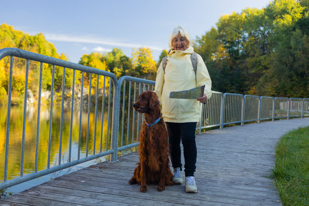 An elderly woman with travel map and dog in autumn nature. High quality photoの写真素材