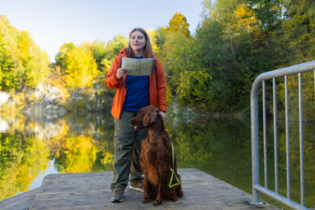 Happy 30s woman hiker hiking in mountain lake. Female with a irish setter dog looking at map and planning trip or get lost. Poland. High quality photoの写真素材