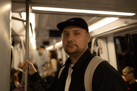 Man standing inside a subway train holding a handrail while commuting on public transportation in...