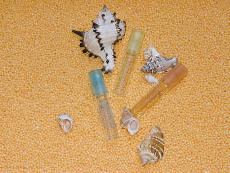 The image of bottles of perfume and cockleshells on a yellow backgroundの写真素材