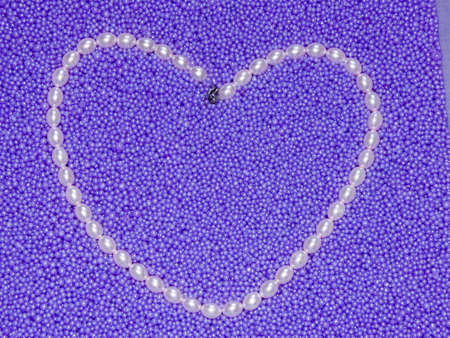 The image heart from pearls beads on a lilac backgroundの写真素材
