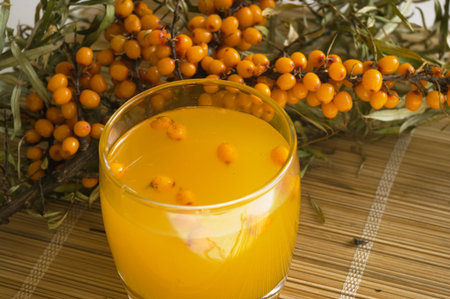 the Image of a glass with juice against sea-buckthorn berries branch
