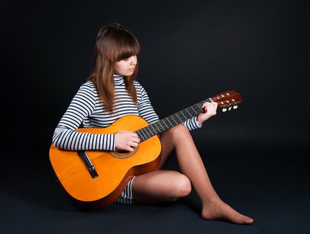 The image of the girl with a guitar on a black backgroundの写真素材