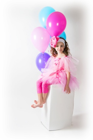 The girl with balloons sits on a white cubeの写真素材