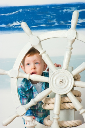 the little boy behind a ship steering wheelの写真素材