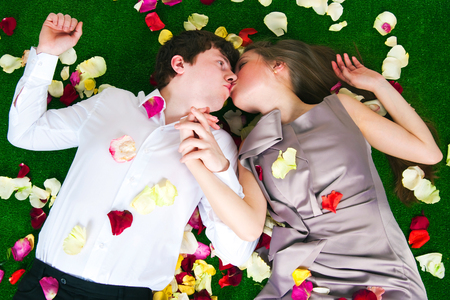 Young enamoured people lie in petals of rosesの写真素材