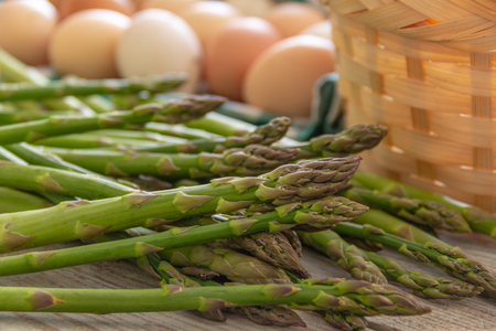 asparagus, on the table and chicken eggs in the backgroundの写真素材
