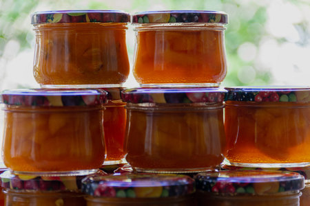pyramid of glass jars filled with apricot jam on the lumen, against the window