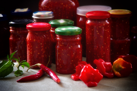 home-made canned vegetables in glass jars and fresh peppersの写真素材