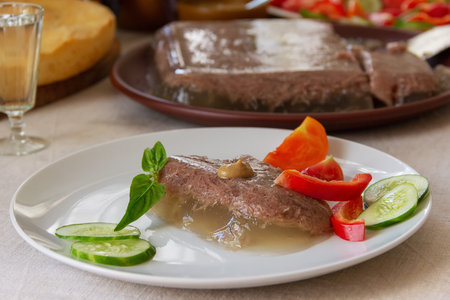 a slice of jelly with mustard and vegetables, and a glass of vodka