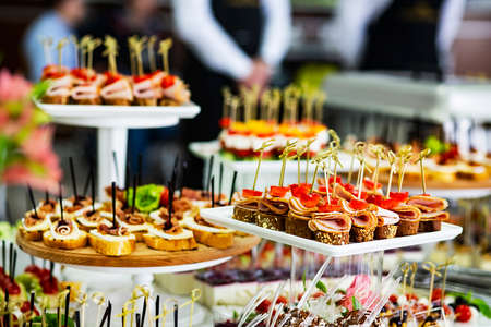 Chic sandwiches with jamon, cheese, ham and vegetables on the buffet table in front of the banquet. Buffet with tapas and apitazers. Festive stl with appetizers in a restaurant. soft focusの写真素材
