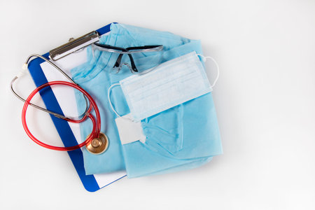 Medical gown, mask, goggles stethoscope and clipboard with the patient's medical history. Protective...