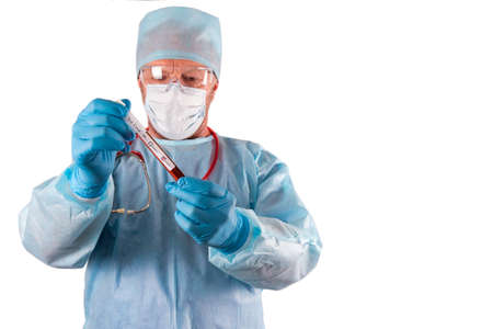 A test tube with a positive test of the patient with a coronovirus in the hands of a doctor in a protective suit, glasses, mask and gloves. Studies of carers during the Covid-19 pandemic. Coronavirus testing copyspaceの写真素材
