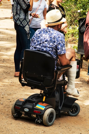 A man with a broken leg in a cast travels in an electric wheelchair. Travel for people with...