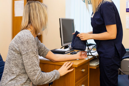 nurse in measures the pressure of the patient with a tonometer in the clinic. measurement of pressure for diagnosis in cardiovascular diseases. pressure testing and medical careの写真素材
