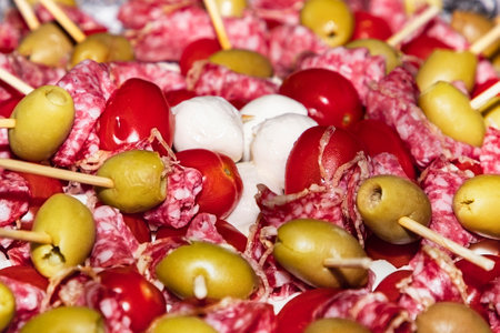 appetizers with sausage, olives and mozzarella on skewers. Buffet with canapes and appetizers on wooden skewers. Sausage, olives, mozzarella cheese served on the buffet table. close up soft focusの写真素材