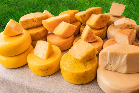 A heads of cheese at the fair. Many heads of cheese on the table covered with linen cloth. Sale of narural farm hard cheese from milk, produced according to traditional technology. Food industryの写真素材