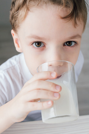 The child drinks milk from a glass. Close-up. Selective focus.の写真素材