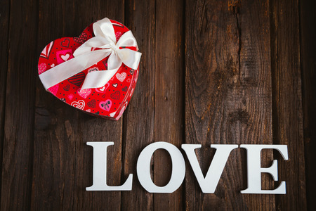 Red gift box with white bow heart shaped for Valentine's day on brown backgroundの写真素材