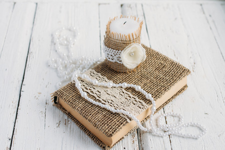 The book is in rustic style on a white table with a candle and a pearl necklaceの写真素材