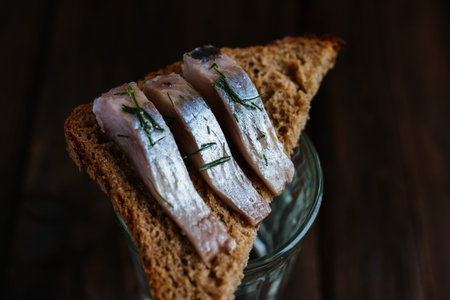 Sandwich with herring, rye bread on a brown table