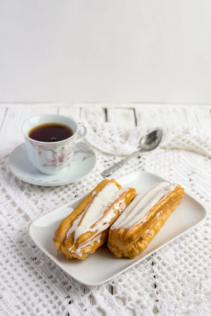 Dessert Eclair with whipped cream and sugar icing on a white table
