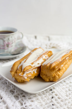 Dessert Eclair with whipped cream and sugar icing on a white table