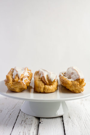 Dessert Eclair with whipped cream and sugar icing on a white table