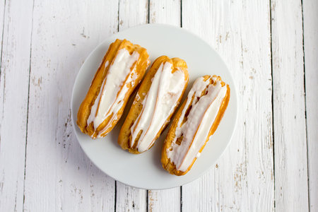 Dessert Eclair with whipped cream and sugar icing on a white table