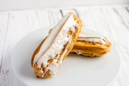 Dessert Eclair with whipped cream and sugar icing on a white table