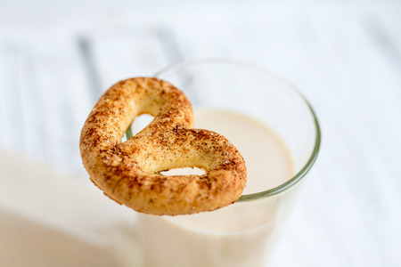 Pretzel with cinnamon and sugar on a white table and a glass of milkの写真素材